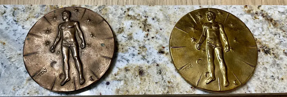 Mitoraj Articulations — two medal variants on marble surface, wide view
