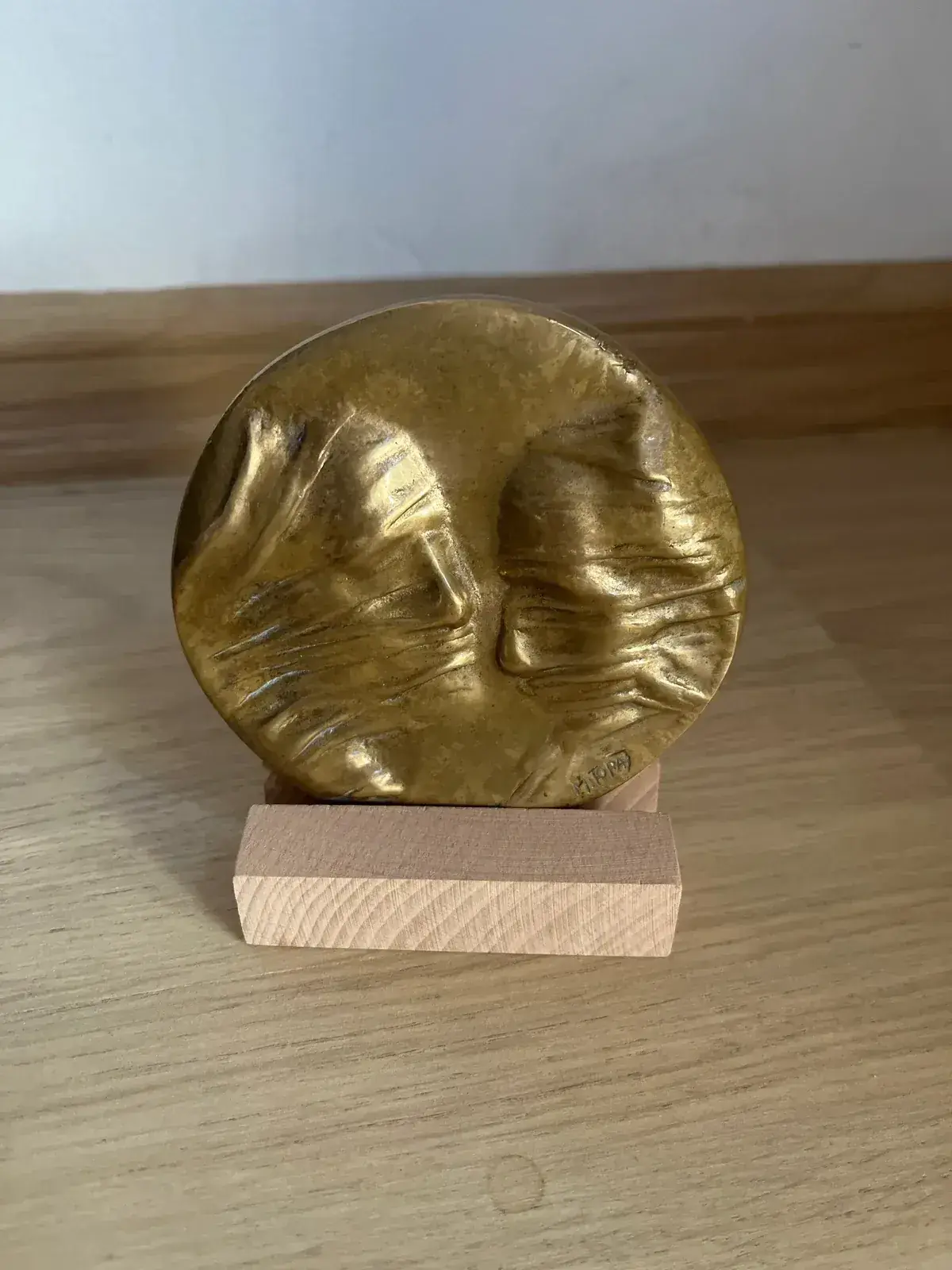La Conversation — Igor Mitoraj, circular gold-patinated bronze relief with two facing profiles on wooden stand
