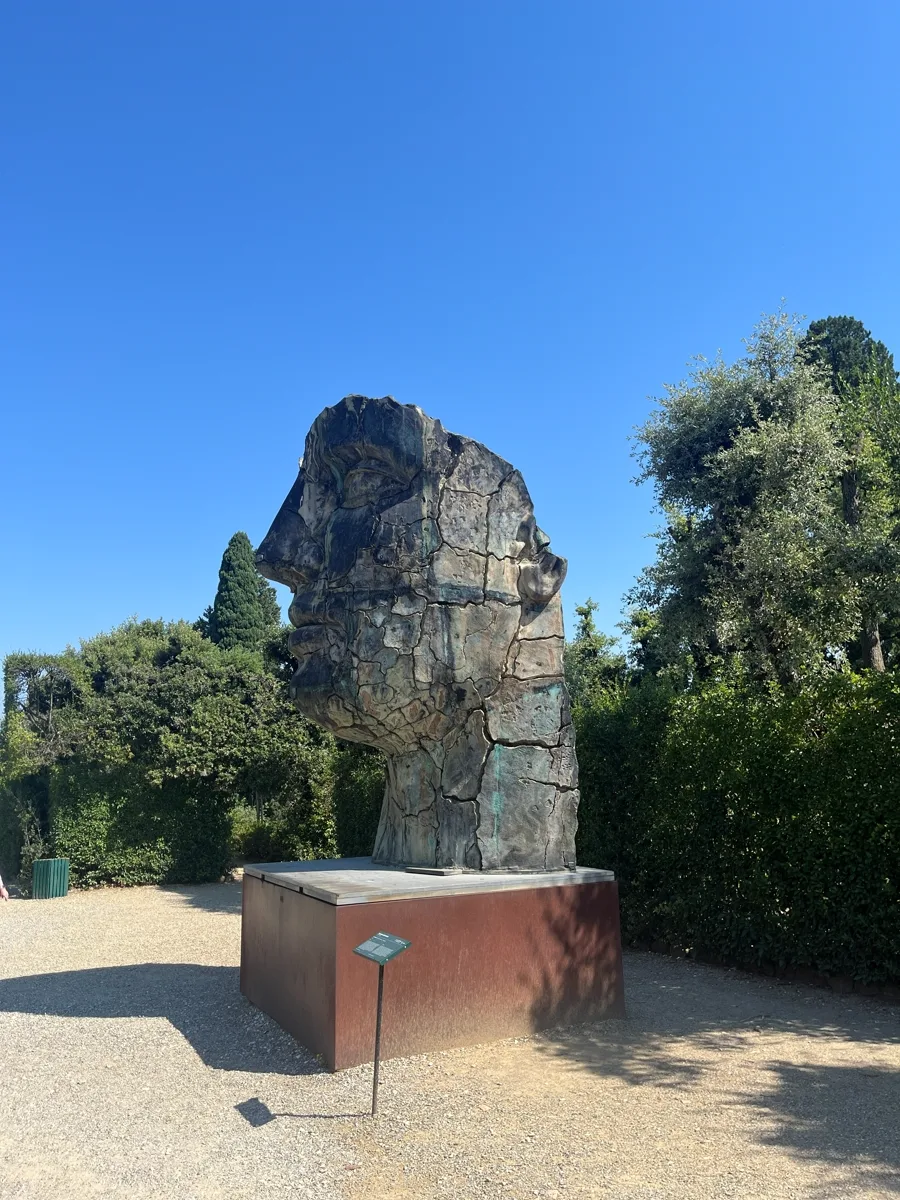 Mitoraj's Tindaro Screpolato photographed from the walkway, the enormous bronze head in half-profile, cracked ridges catching the sun on its right side