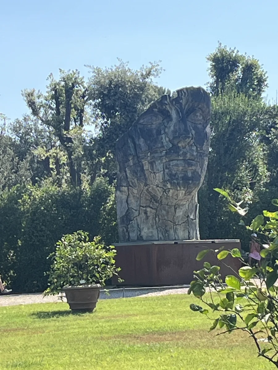 Tindaro Screpolato seen from the upper Boboli lawn with a potted lemon tree in the foreground, cypresses framing the cracked bronze against a clear sky