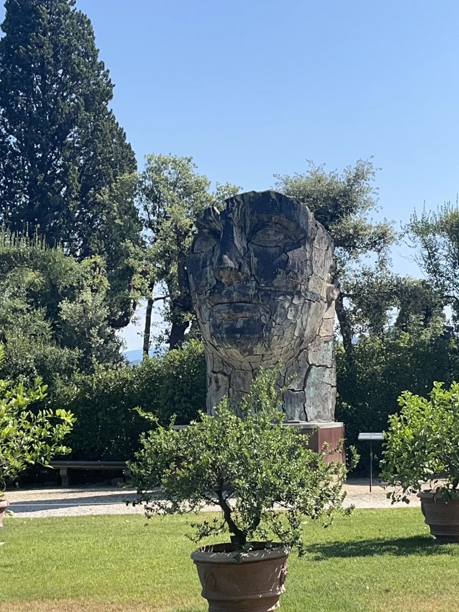 Tindaro Screpolato seen from the citrus grove on the upper Boboli terrace, the sculpture framed by potted lemon trees and cypresses, distant hills faintly visible