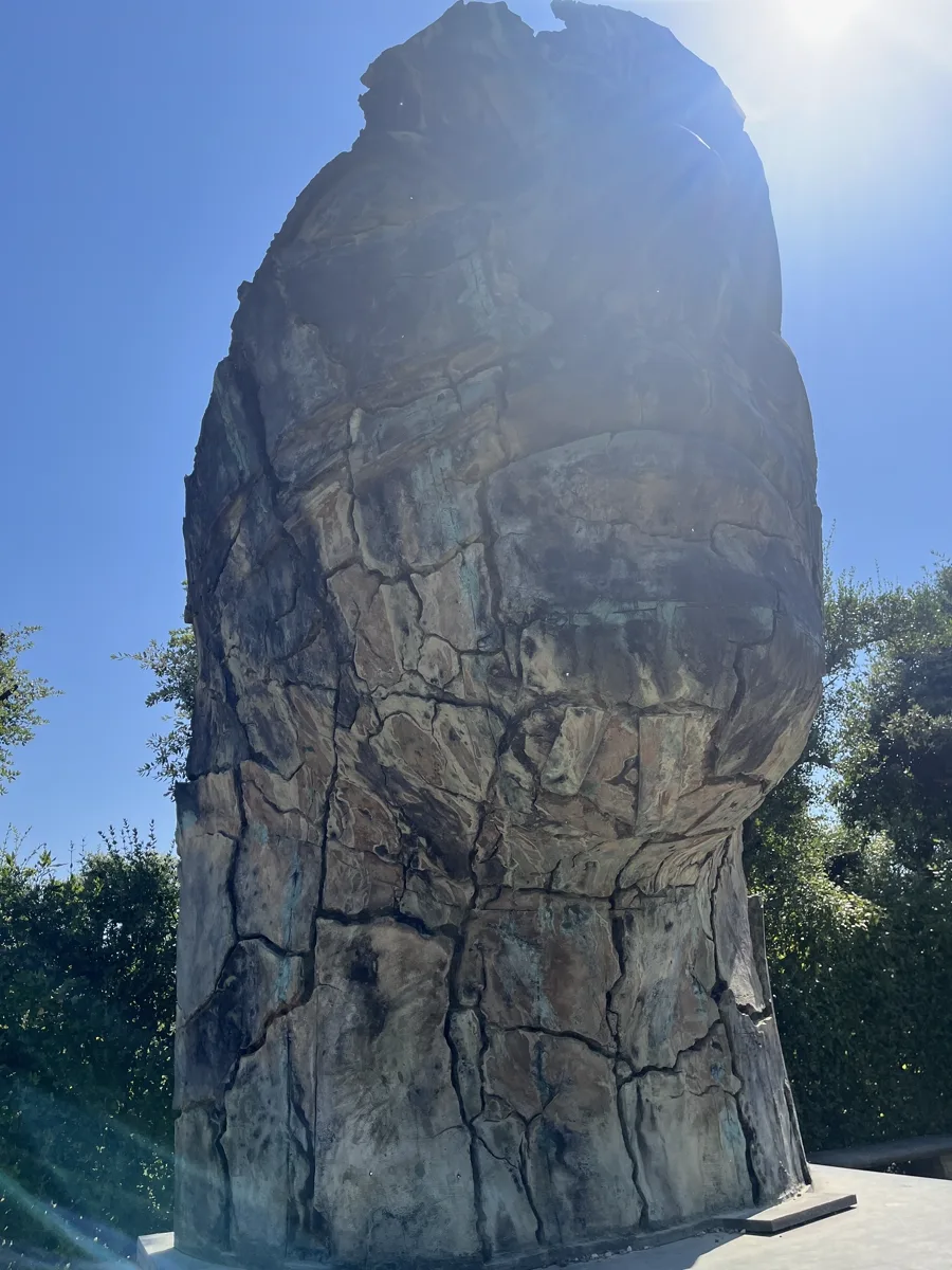 Tindaro Screpolato (1997) by Igor Mitoraj — dramatic upward angle against the sun, Boboli Gardens, Florence