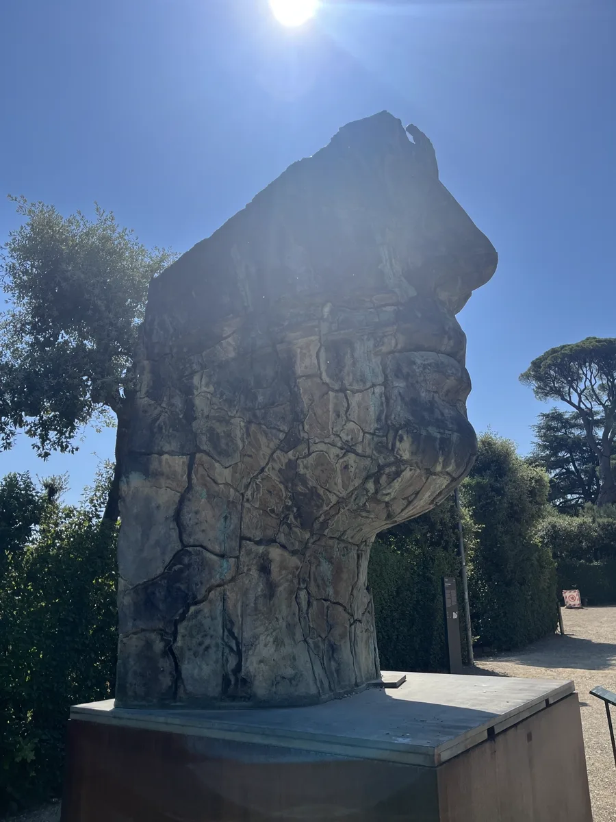 Side profile of Tindaro Screpolato against a high summer sun, the cracked surface catching light on its left flank while the outline reads as an eroded ancient fragment